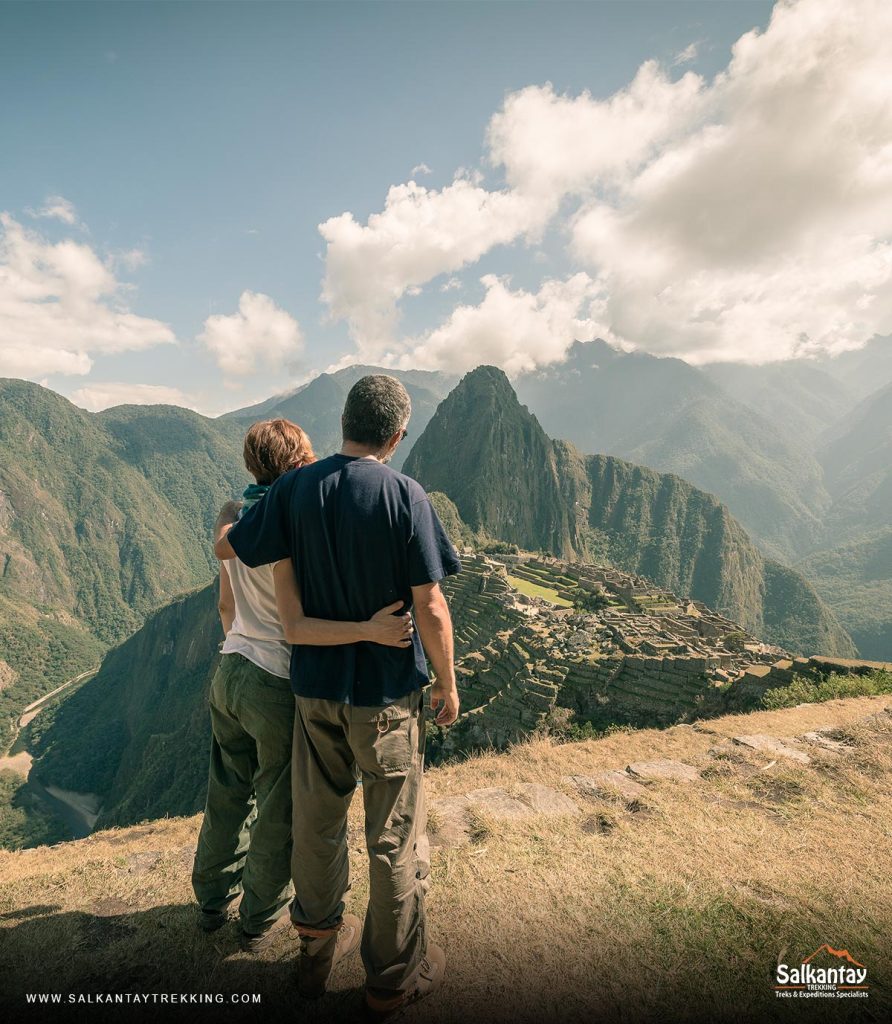 Una pareja de turistas abrazados mirando Machu Picchu