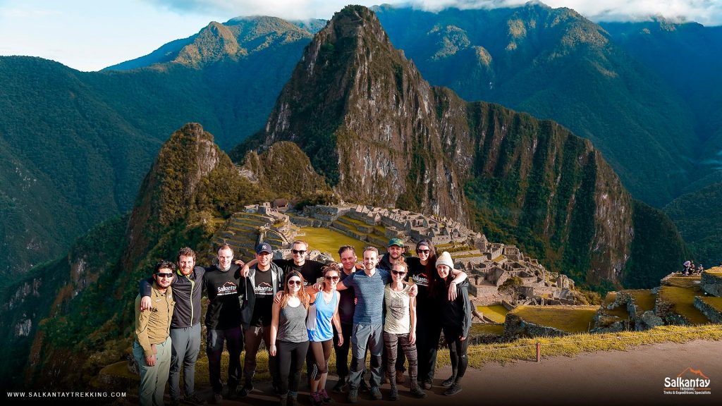 Grupo de tuistas posando para una foto con Machu Picchu al fondo.