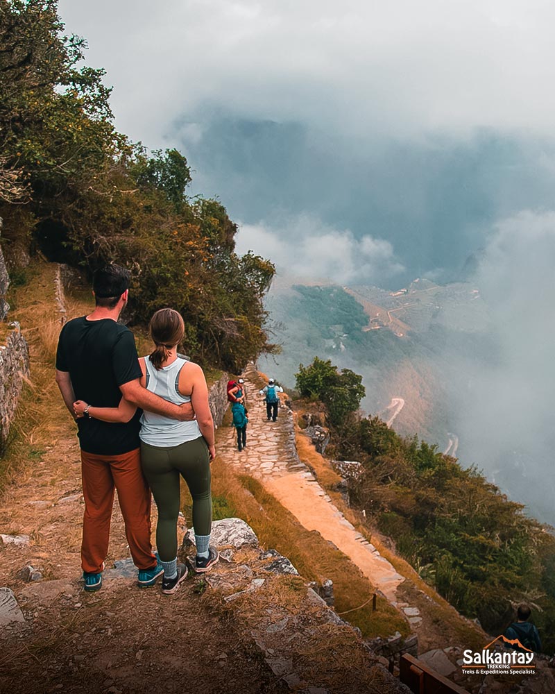 Una pareja de turistas contemplando la ciudadela de Machu Picchu desde la Puerta del Sol o Inti Punku.