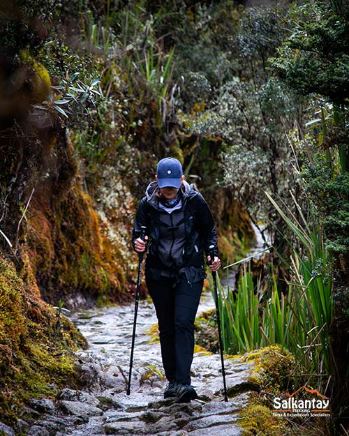 Mujer caminando con bastones de trek en el Camino Inca