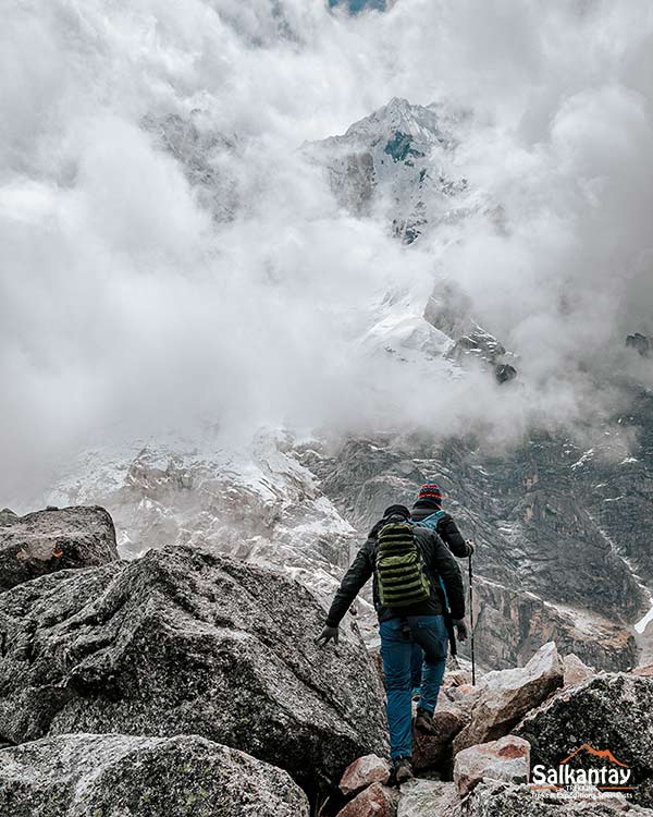 Dos personas viajeras subiendo el Paso Salkantay. Caminata Salkantay a Machu Picchu