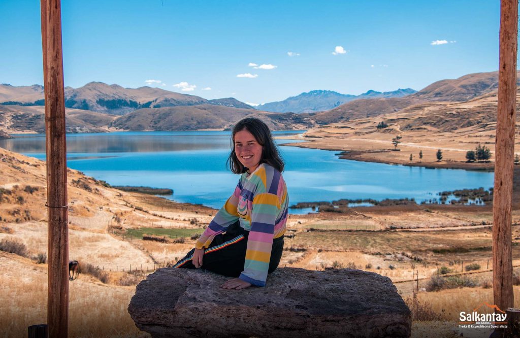 Turista sentada con el fondo de las cuatro lagunas de Q'eswachaka