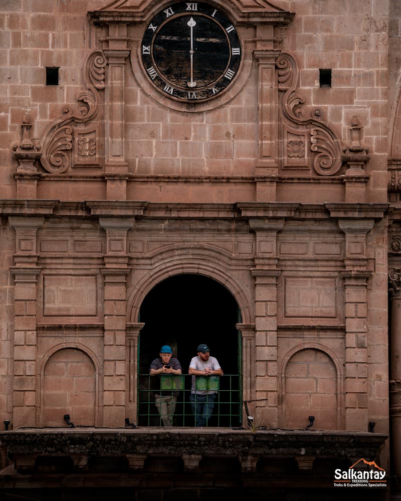 Dos turistas en una ventana de la iglesia de la Compañía de Jesús situada en la plaza principal de Cusco.