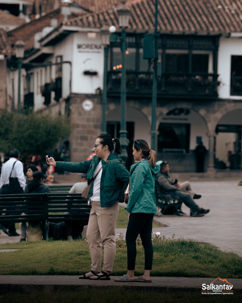 Dos turistas tomándose un selfie en la plaza principal de la ciudad de Cusco.