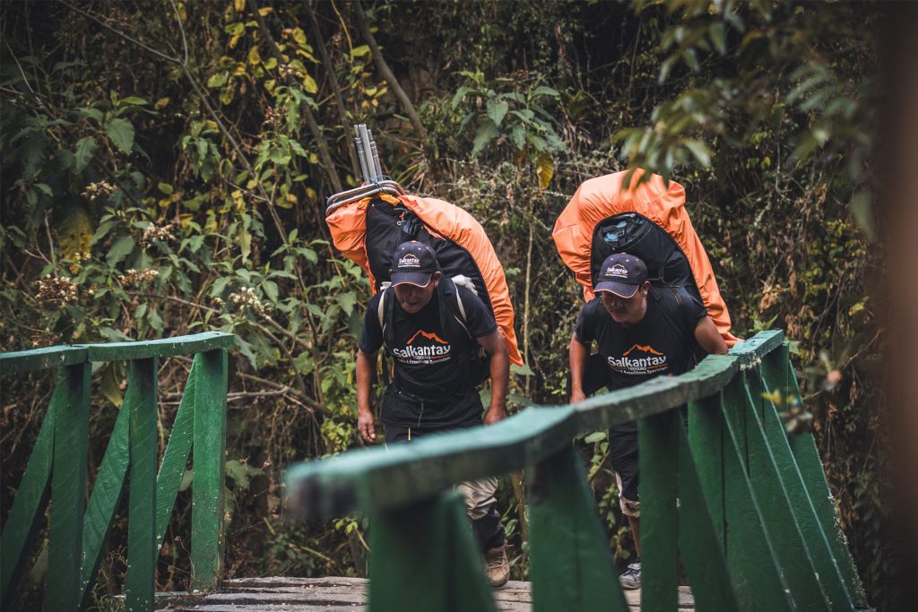 Dos porteadores cruzando un puente de madera en el Camino Inca
