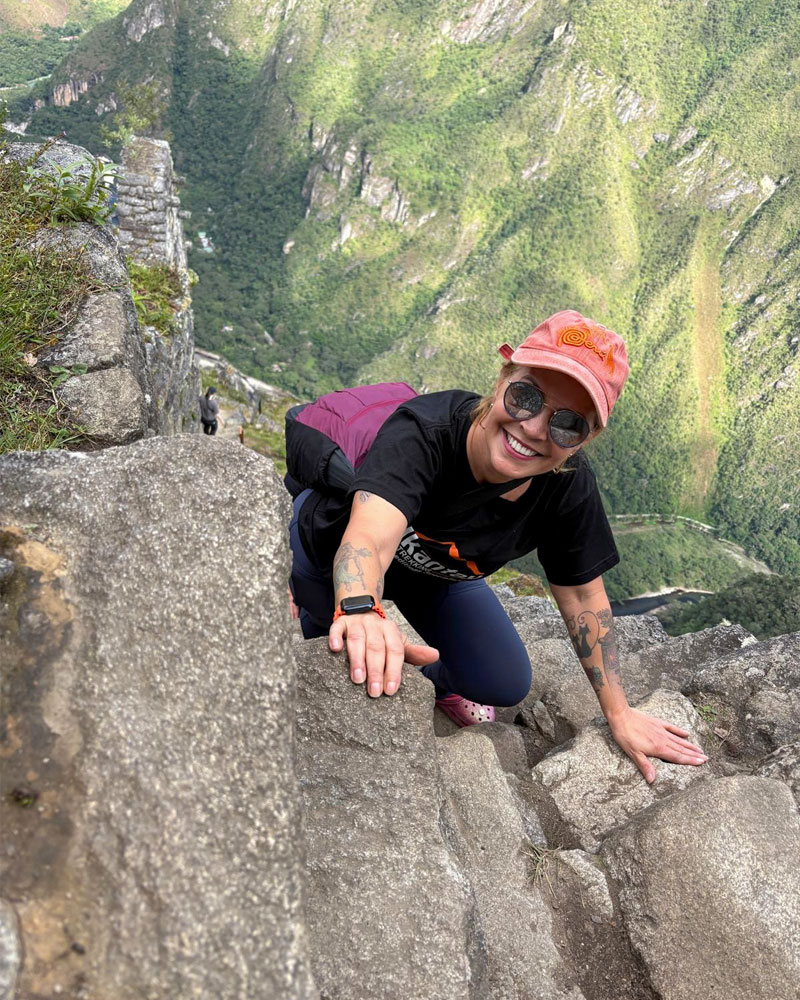 Mujer posando feliz en las famosas escalinatas de la muerte en la montaña Huayna Picchu