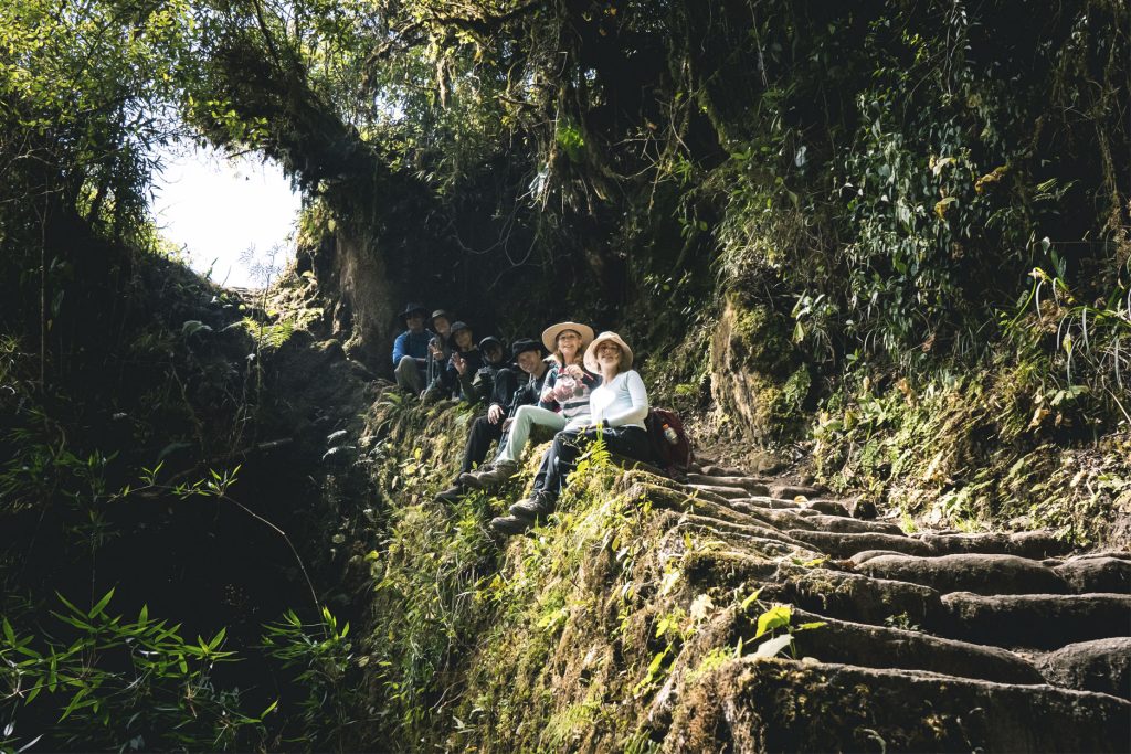 Personas felices sentadas en las escalinatas del Camino Inca