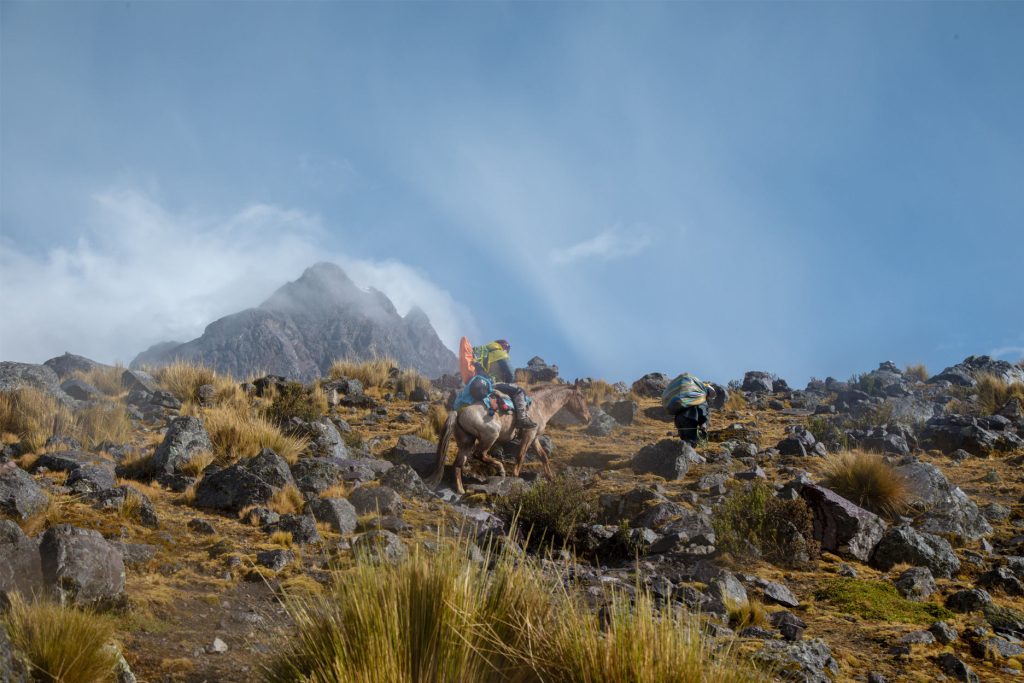Turista montado en un caballo y su arriero en la caminata a la montaña Ausangate