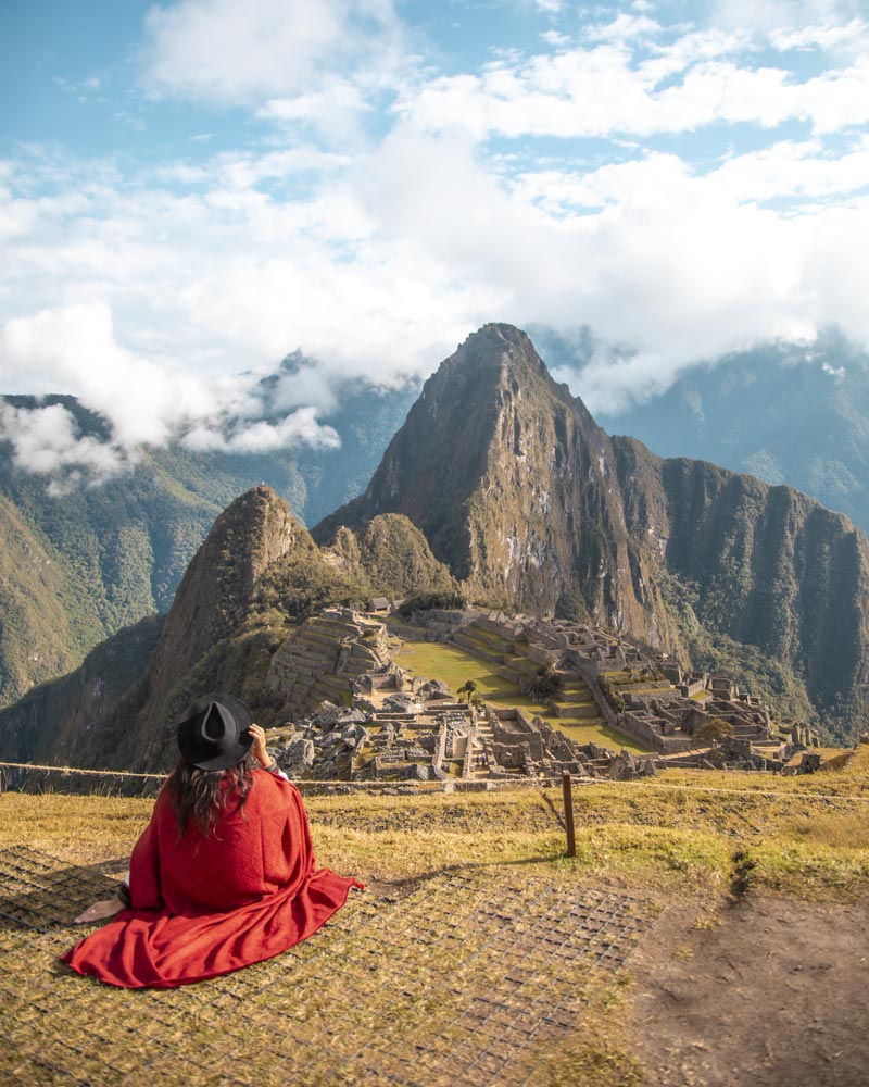 Turista con poncho andino de color rojo en la ciudadela de Machu Picchu