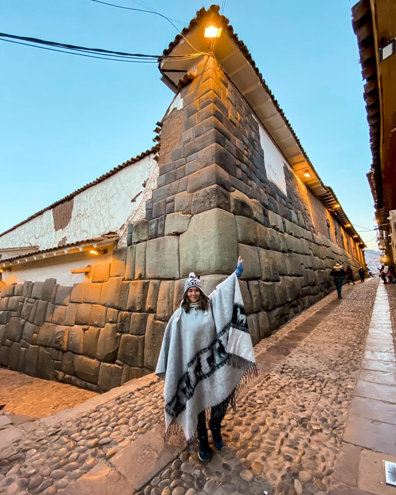 Turista con poncho andino en la piedra de 12 ángulos