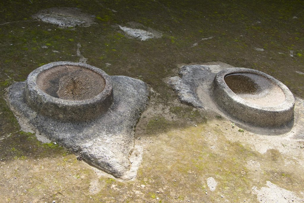 Fotografía de los espejos de agua en Machu Picchu, dos piedras con tallado similar ubicadas en el centro de un recinto