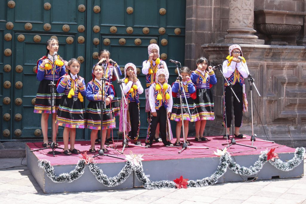 Coro de niños cantando villancicos en Cusco con trajes tipicos