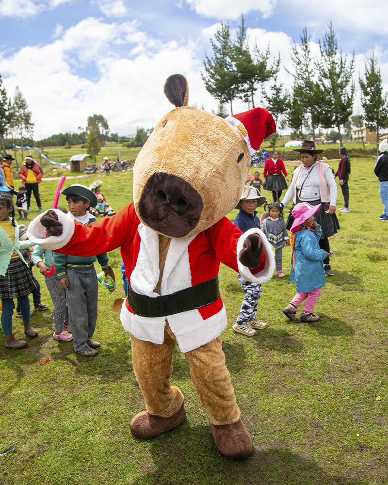 Foto de un muñeco navideño con niños andinos alrededor, en una chocolatada por navidad