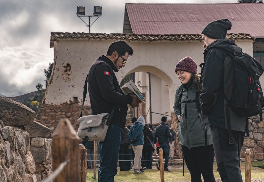 Pareja de turistas con su guía recorriendo el complejo arqueológico de Chinchero 