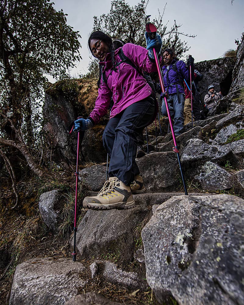 Turistas descendiendo escalinatas inca en Machu Picchu con bastones de trekking