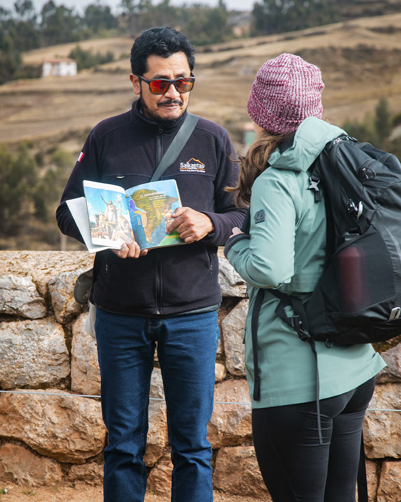 Guia de turismo de Salkantay Trekking explicando a una turista en el sitio arqueologico de Chinchero la historia y arquitectura de la epoca