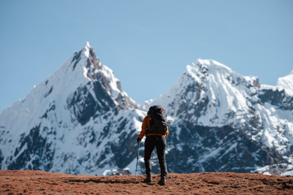 Excursionista en los Andes peruanos, rodeado de montañas nevadas, disfrutando de una desconexión digital en plena naturaleza