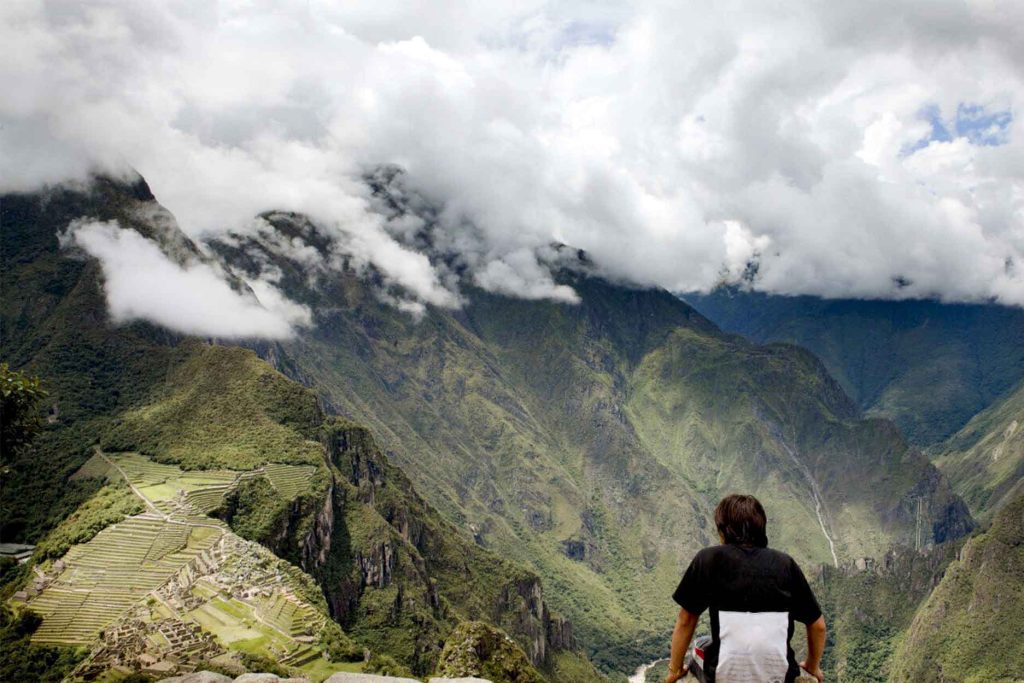 turista respirando mientras observa la ciudadela inca de Machu Picchu