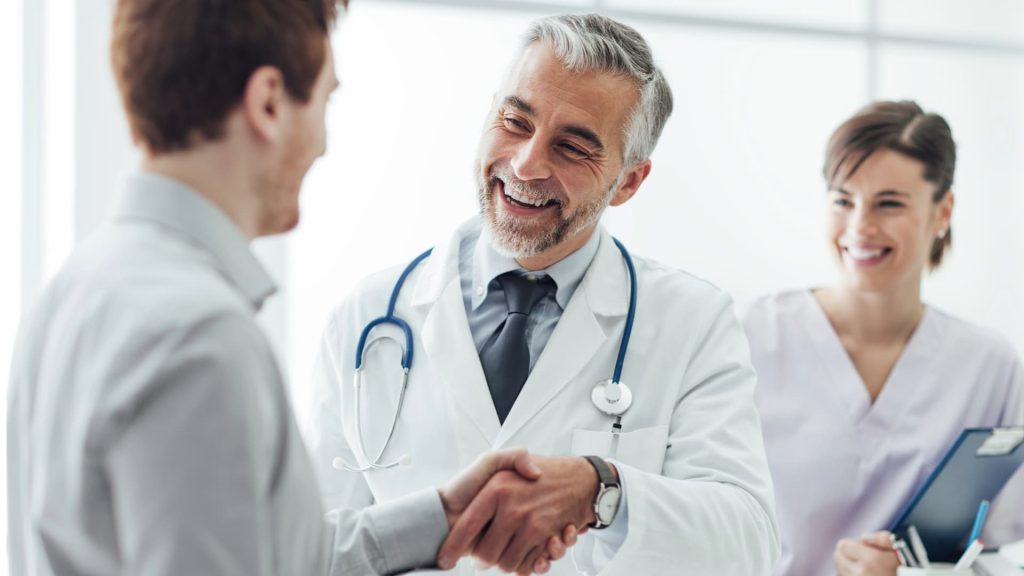 Un paciente hablando con su médico durante una consulta médica en el consultorio de una clínica.