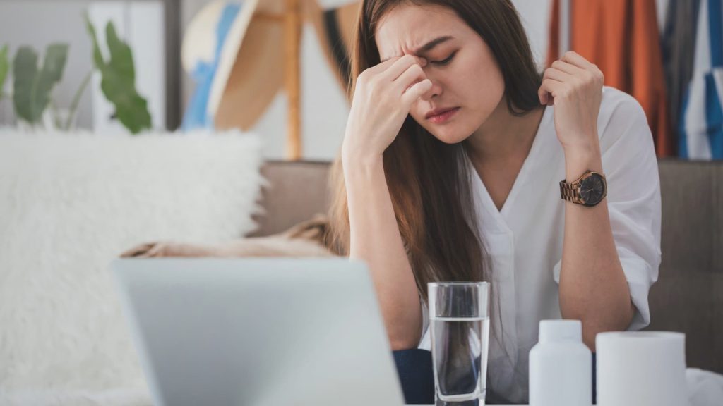 Una persona se agarra la frente con expresión de dolor debido a un fuerte dolor de cabeza.