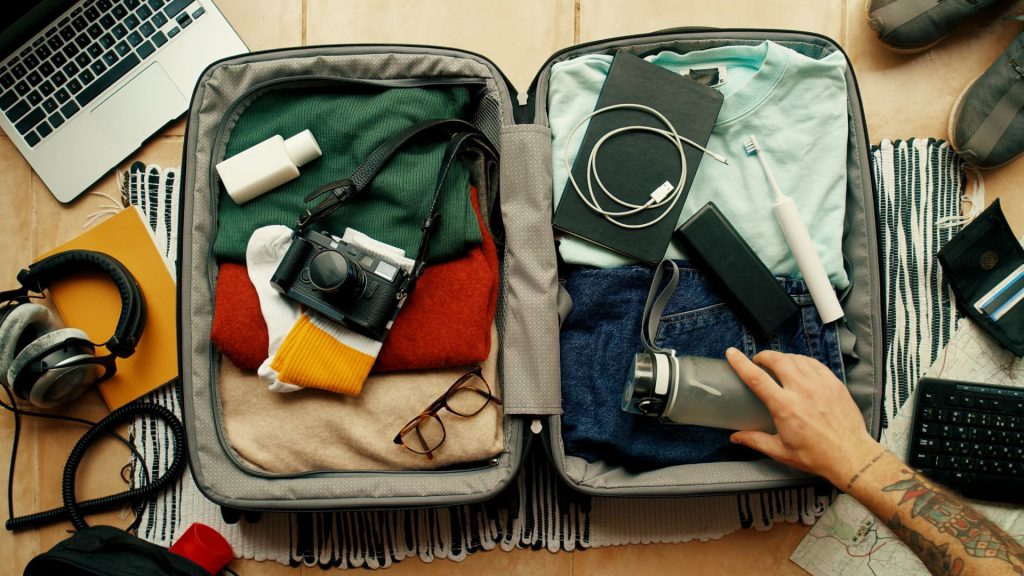 Un viajero que organiza y guarda con cuidado la ropa y el equipo en una mochila de senderismo.