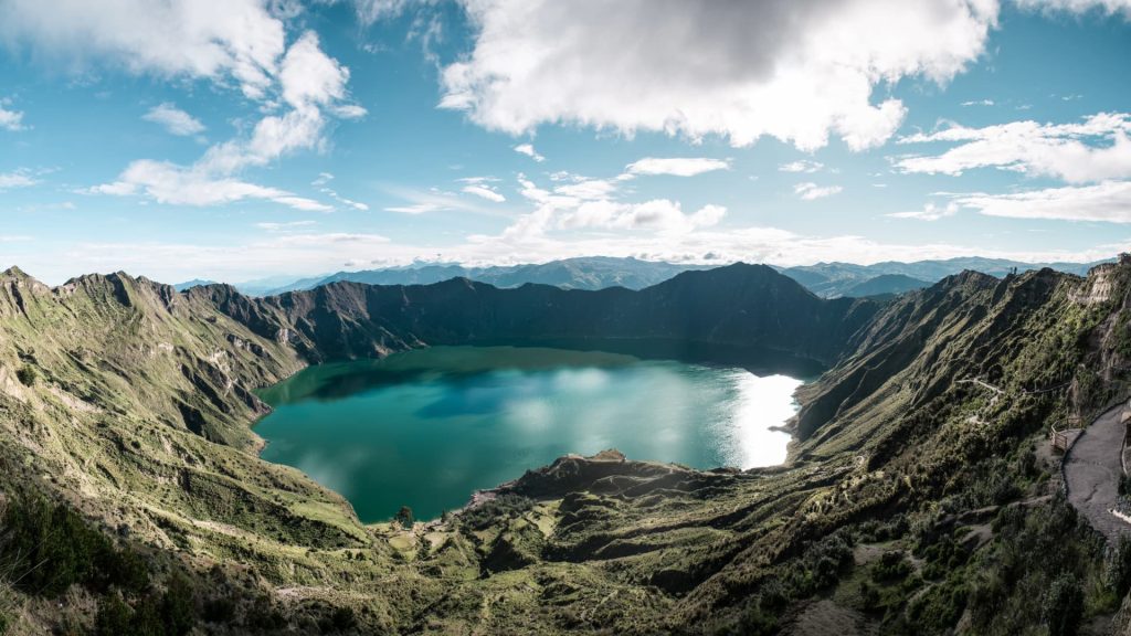 Una vista panorámica del enorme lago volcánico de color verde esmeralda del cráter de Quilotoa bajo un cielo nublado.