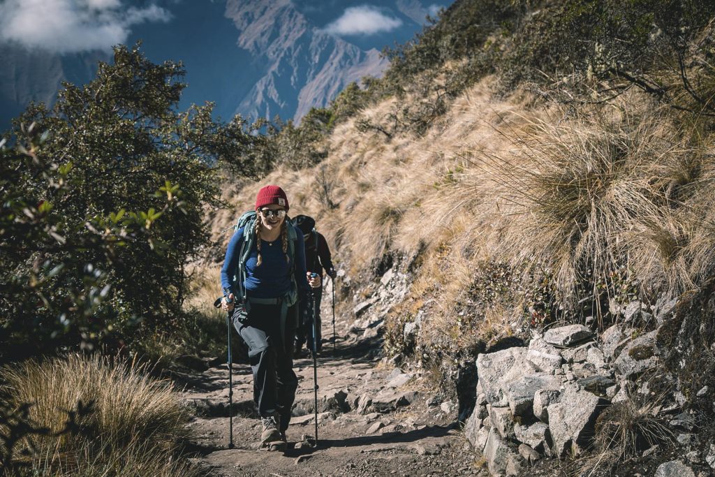 Mujer caminando con bastones de trekking por el Camino Inca hacia Machu Picchu