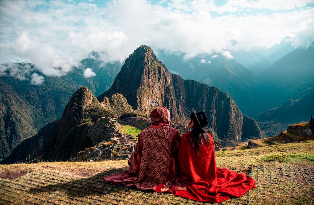 Un turista de pie, contemplando la ciudadela de Machu Picchu desde lo alto.