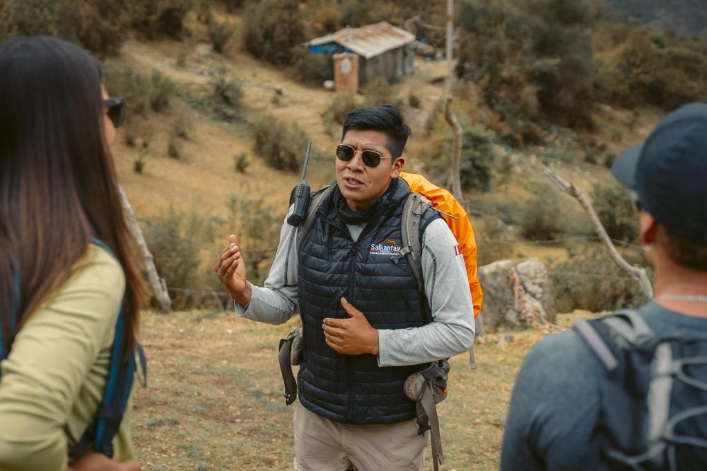 Guía turístico explicando la ruta de senderismo del camino Salkantay a un grupo de turistas.