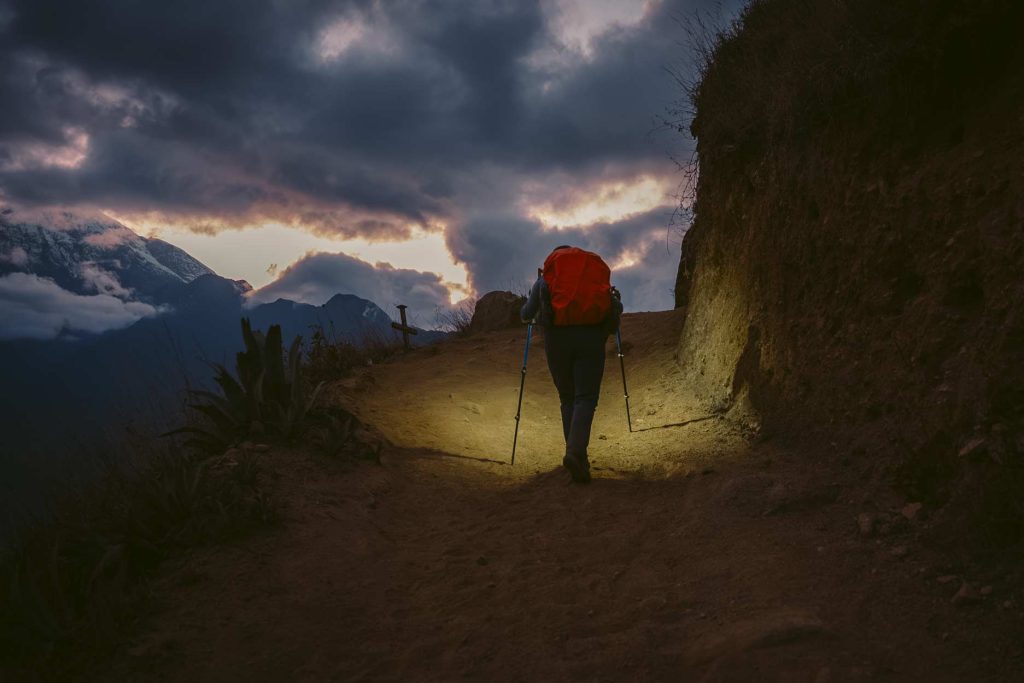 Turista caminando con linterna al atardecer en la caminata a Choquequirao