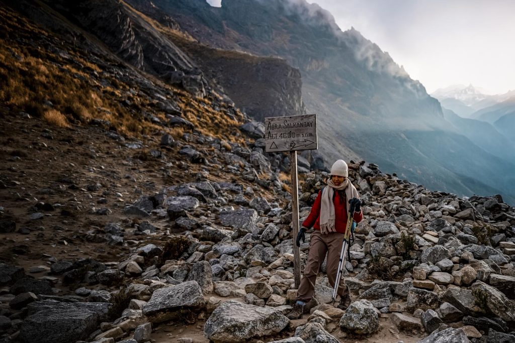 Turista solitario junto a un cartel en el paso de Salkantay.
