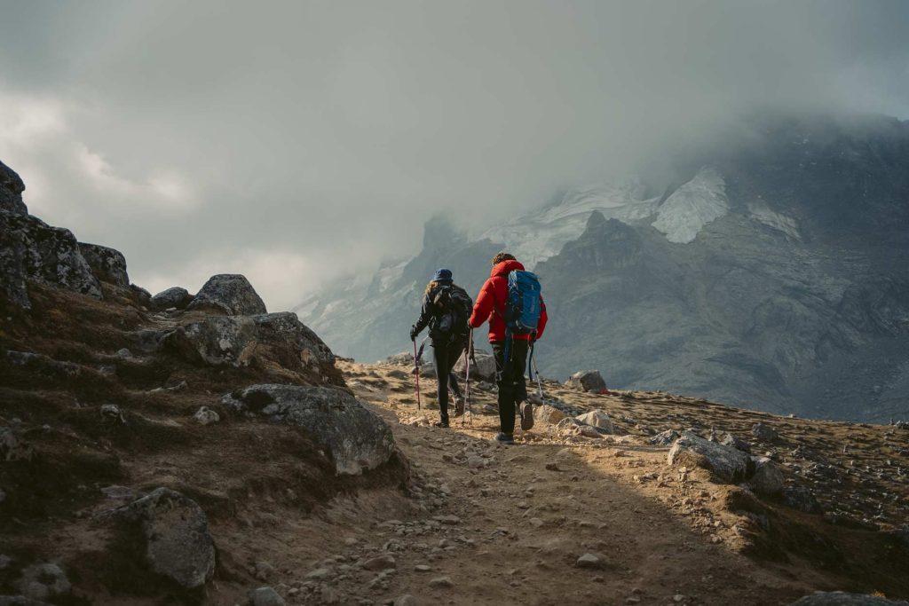 Pareja de turistas caminando al paso Salkantay con equipo completo de montanismo