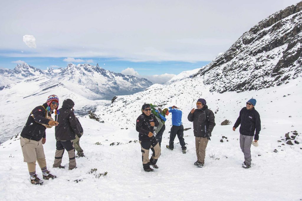 Turistas y personal de caminata disfrutan del senderismo en la ruta de Ausangate en medio de la nieve.