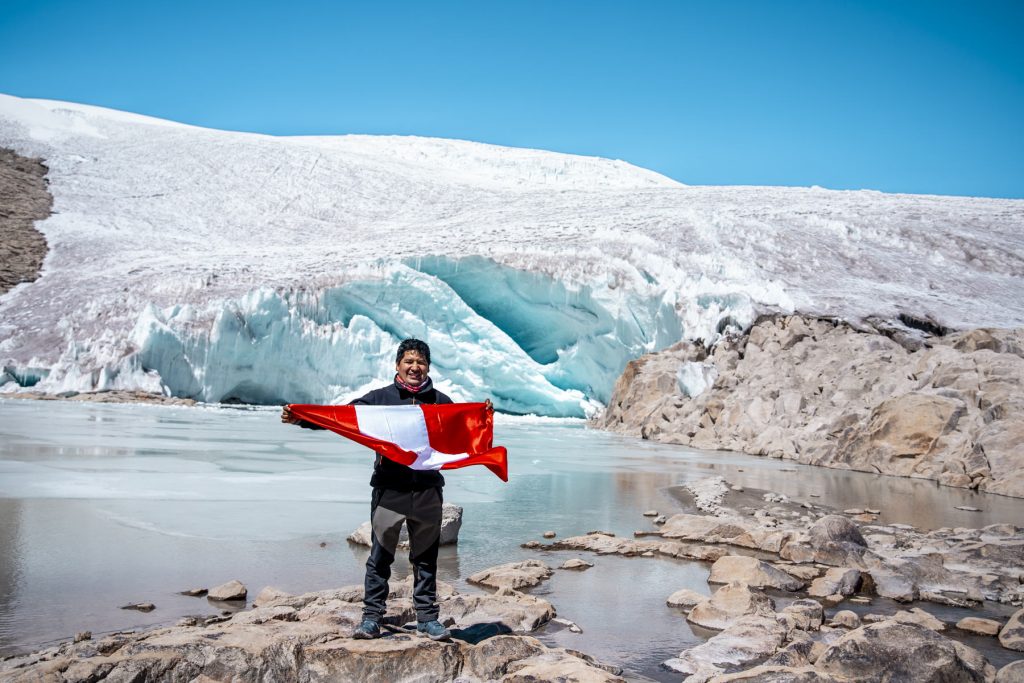 Turista con su bandera peruana con el glaciar Quelccaya de fondo.