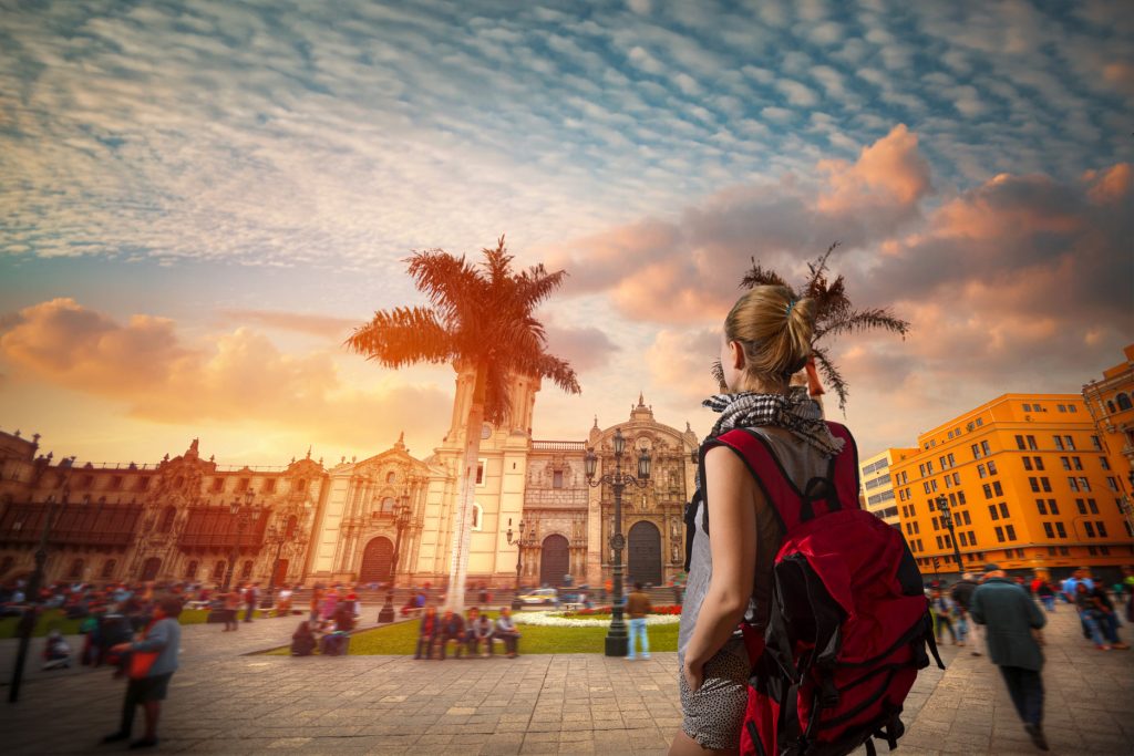 Turista con su mochila roja en la plaza principal de Lima.