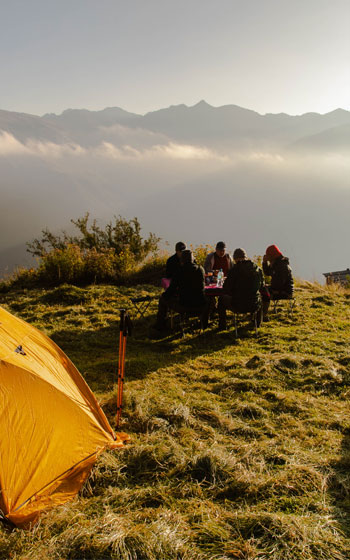 Vista panorámica de turistas disfrutando de un desayuno al aire libre con vista a las montañas andinas, cerca del sitio arqueológico Huchuy Qosqo.