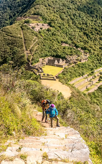 Dos turistas explorando las ruinas y estructuras de la Ciudadela Inca de Choquequirao.