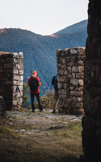 Dos turistas explorando un sitio arqueológico inca en la ruta del Camino Inca hacia Machu Picchu.