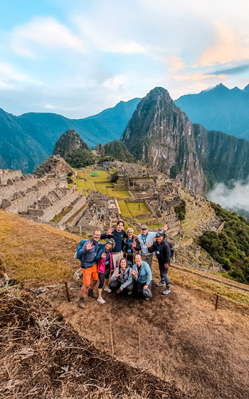 Foto panorámica de un grupo de turistas en la antigua ciudadela inca de Machu Picchu, capturando las impresionantes vistas y la belleza atemporal del sitio más icónico del Perú.