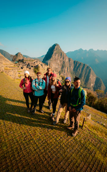Grupo de turistas visitando la impresionante ciudadela inca de Machu Picchu, admirando sus antiguas construcciones y el imponente paisaje andino.