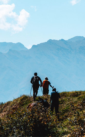 Grupo de turistas en ruta de trekking hacia el sitio arqueológico de Huchuy Qosqo, disfrutando del paisaje y la rica herencia cultural de los Andes de Perú.