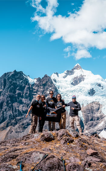 Grupo de turistas haciendo trekking por la Ruta de Lares, con majestuosos nevados de fondo, disfrutando de la aventura en los Andes de Perú.