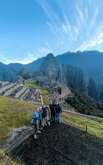 Grupo de turistas explorando la antigua Ciudadela Inca de Machu Picchu, admirando su impresionante arquitectura y el espectacular paisaje de Perú.