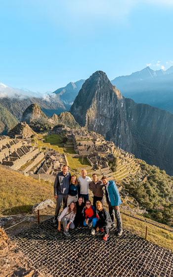 Grupo de turistas posando con la magnífica Ciudadela Inca de Machu Picchu de fondo, el hito más icónico de Perú.