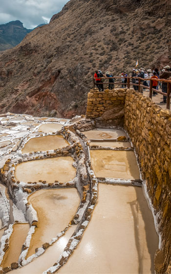 Grupo de turistas observando las salineras de Maras, un impresionante conjunto de pozas de sal tradicionales ubicado en las montañas del Valle Sagrado de los Incas.