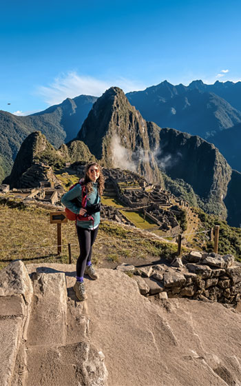 Mujer turista disfrutando de la impresionante vista panorámica de la Ciudadela Inca de Machu Picchu, el destino más icónico de Perú.