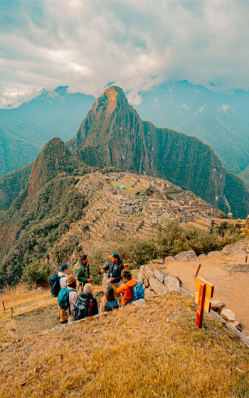 Foto panorámica de un grupo de turistas disfrutando de la vista de la majestuosa Ciudadela Inca de Machu Picchu.