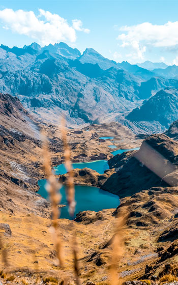 Vista panorámica de las lagunas cristalinas y las montañas andinas a lo largo de la Ruta de Lares, mostrando la serena belleza de la sierra peruana.