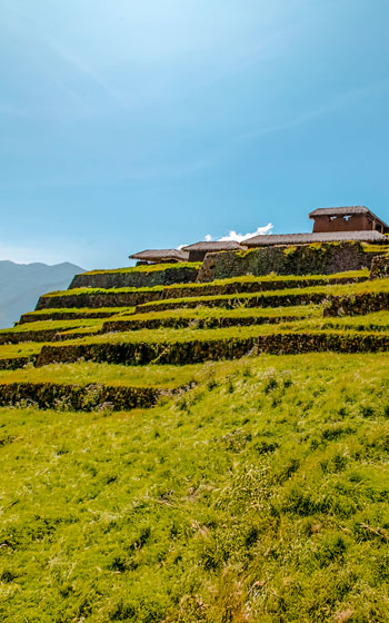 Vista panorámica de las antiguas terrazas agrícolas incas en el sitio arqueológico de Huchuy Qosqo, rodeadas por los majestuosos Andes de Perú.