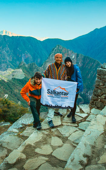 Pareja de turistas con su guía en Inti Punku (Puerta del Sol), observando la majestuosa ciudadela de Machu Picchu.